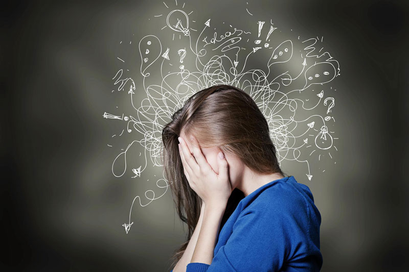 Osoba sa ADHD drži glavu sa ilustracijama misli i pitanja koja simbolizuju mentalni haos