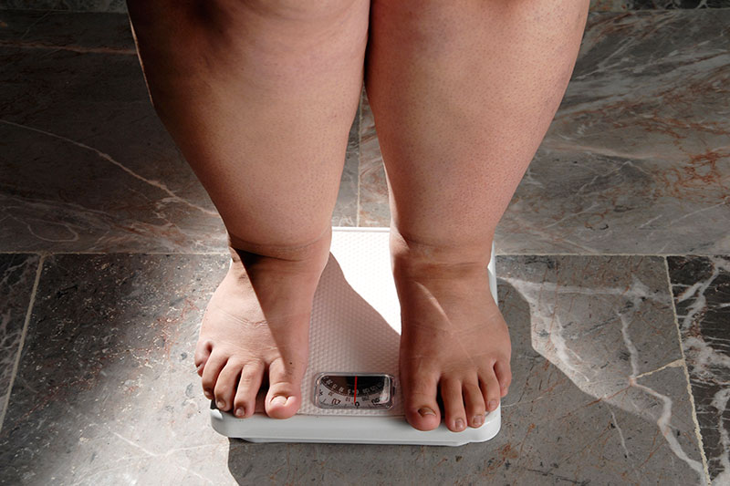 Osoba stoji na vagi pokazujući merenje težine, povezano sa homeopatskim lekovima za mršavljenje